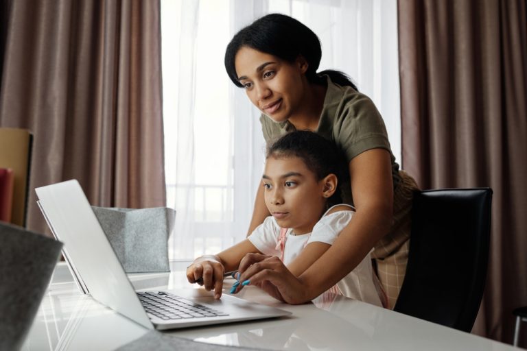 parent helping daughter with online school